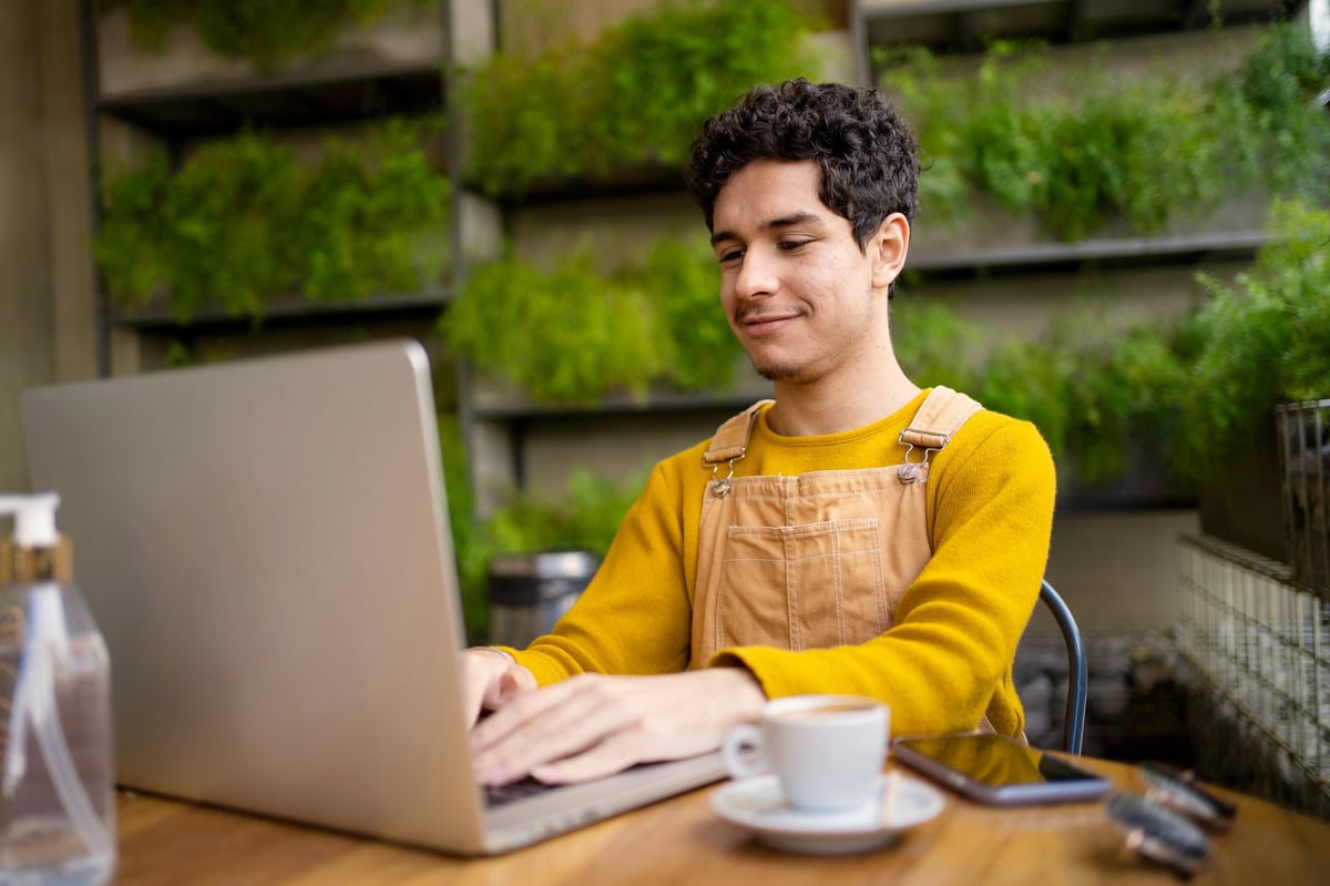 Small business owner working on laptop at a local café — a website gives independent businesses a digital home customers can find any time