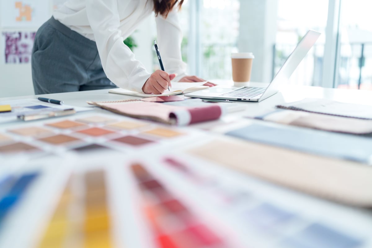 Web designer sketching UI ideas and wireframes at a modern creative workspace with laptop and notebook