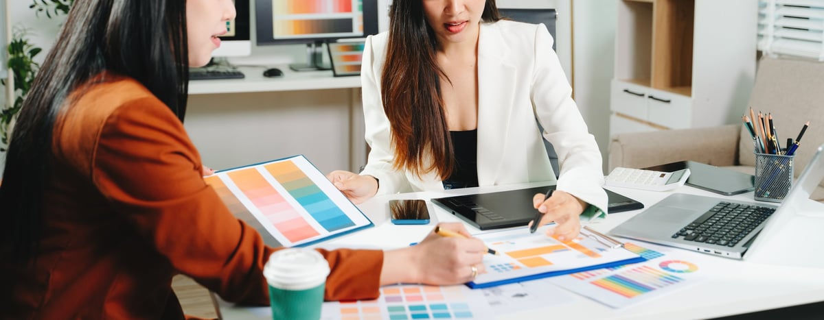 Two designers collaborating on brand identity and UX design in a modern creative studio