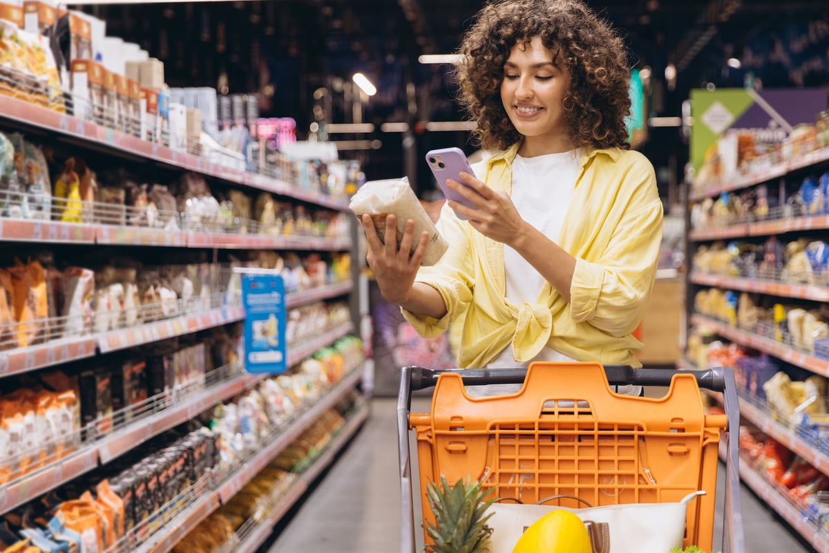Customer using smartphone to research products while shopping — customers often check details on their phones before they visit or buy